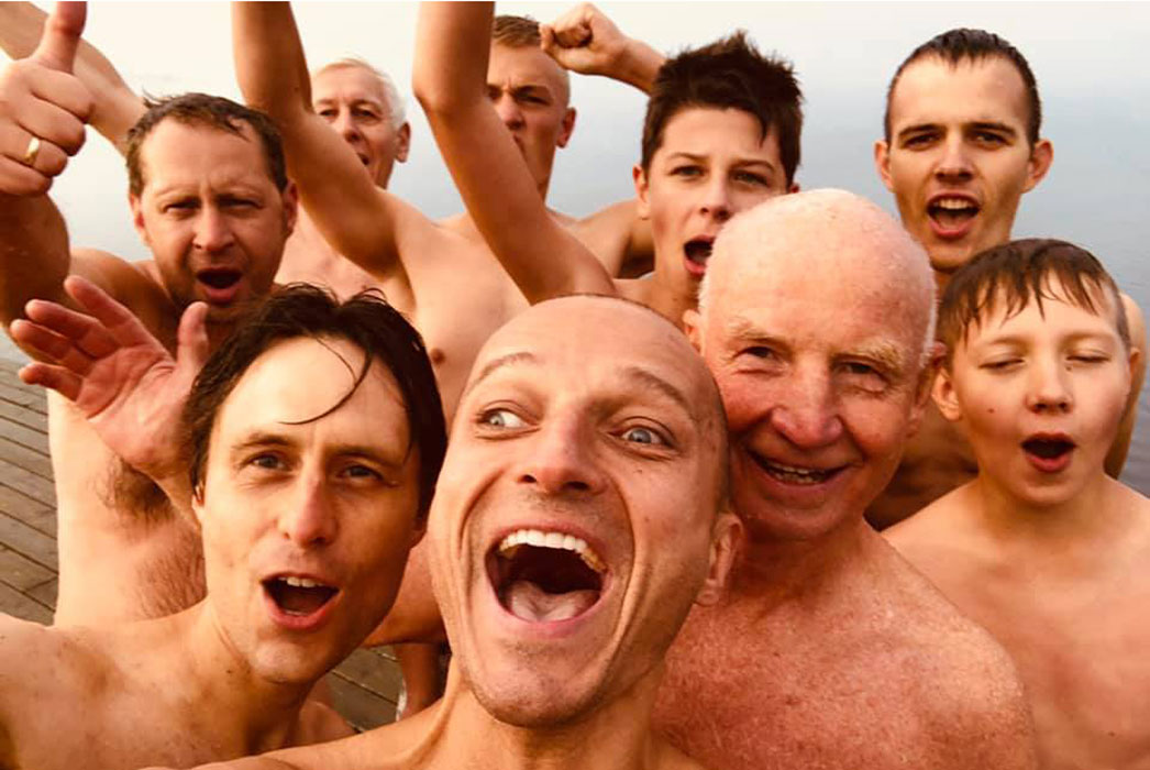Portrait of nine men, no shirts, and in high spirits.