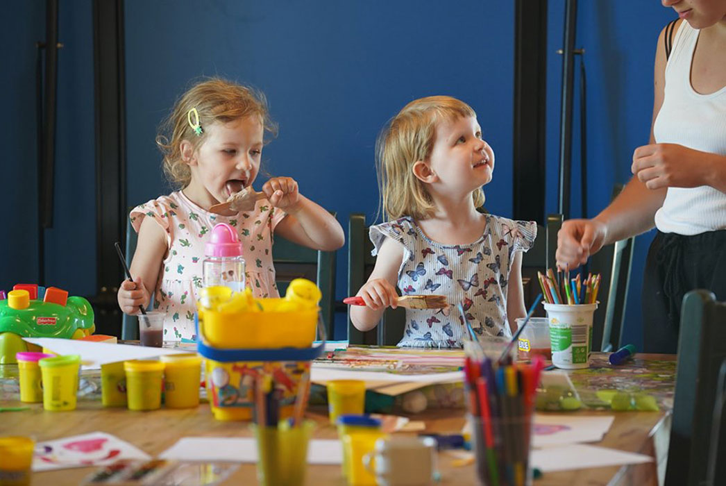 Two young girls playing with paint and bright colours