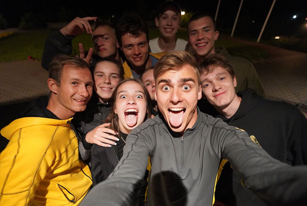 Selfie of 10 young men and women, smiling in the dark, flash from the camera